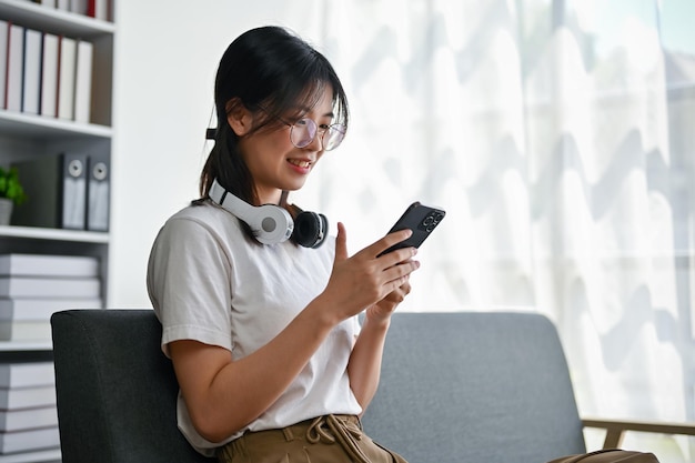 Vista traseira de uma jovem asiática feliz conversando com seus amigos em seu telefone