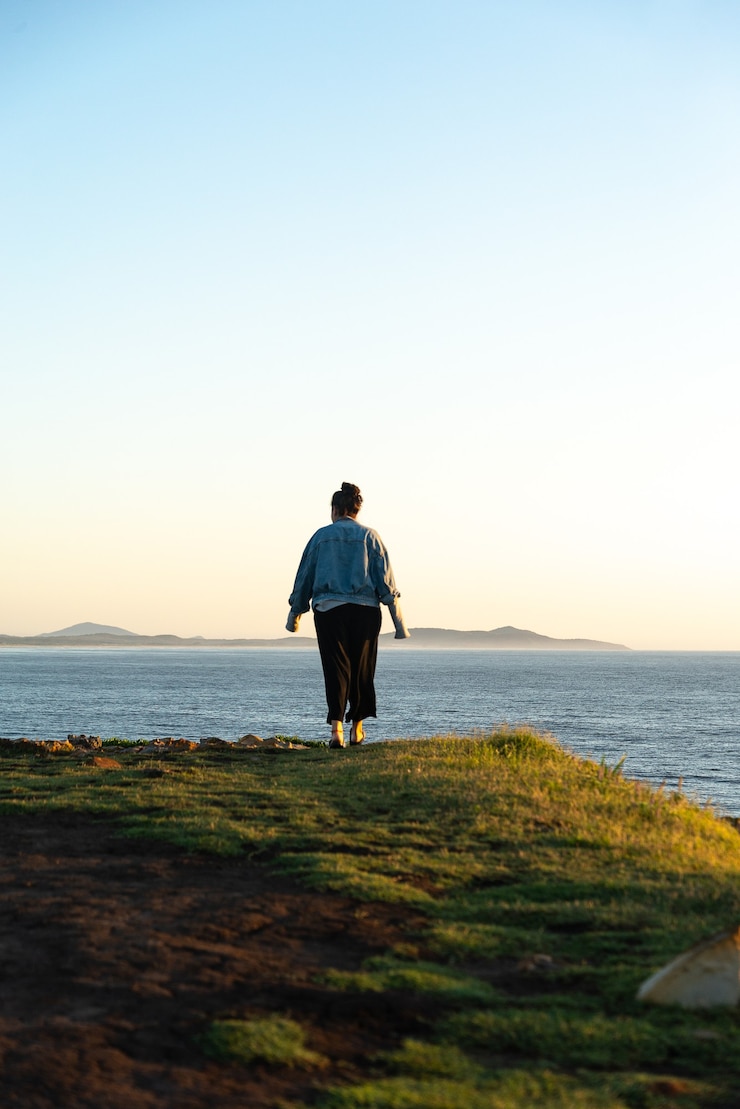 Foto vista traseira de uma jovem caminhando sobre o penhasco na paisagem do mar. aventura ao ar livre