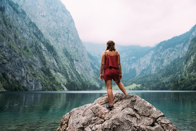 Vista traseira de uma jovem de pé no lago contra a montanha