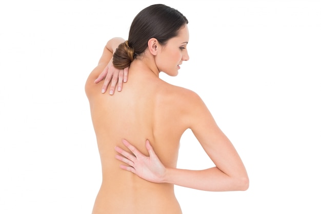 Vista traseira de uma jovem em forma de topless com dor nas costas