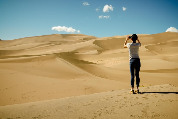 Vista traseira de uma jovem fotografando o deserto
