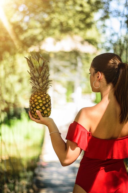 Foto vista traseira de uma jovem mulher segurando um abacaxi