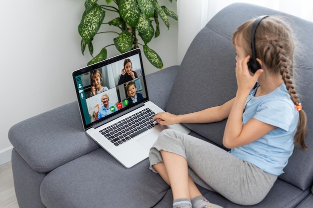 Vista traseira de uma jovem sentada em casa, conversando com uma aula de videochamada on-line com professor ou tutor, estudante adolescente envolvida em conversa de webcam, estude aplicativo de conferência web de uso distante no laptop