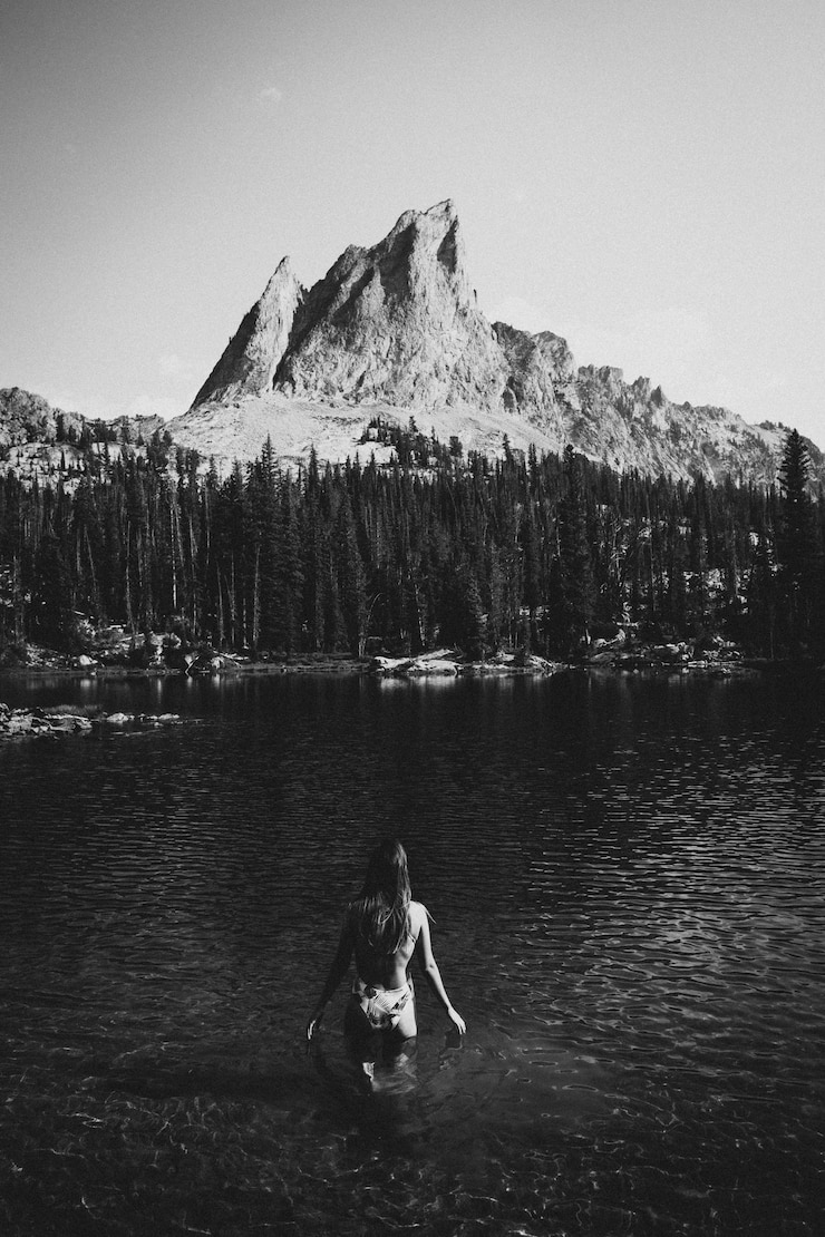 Foto vista traseira de uma jovem vestindo biquíni de pé no lago contra o céu claro