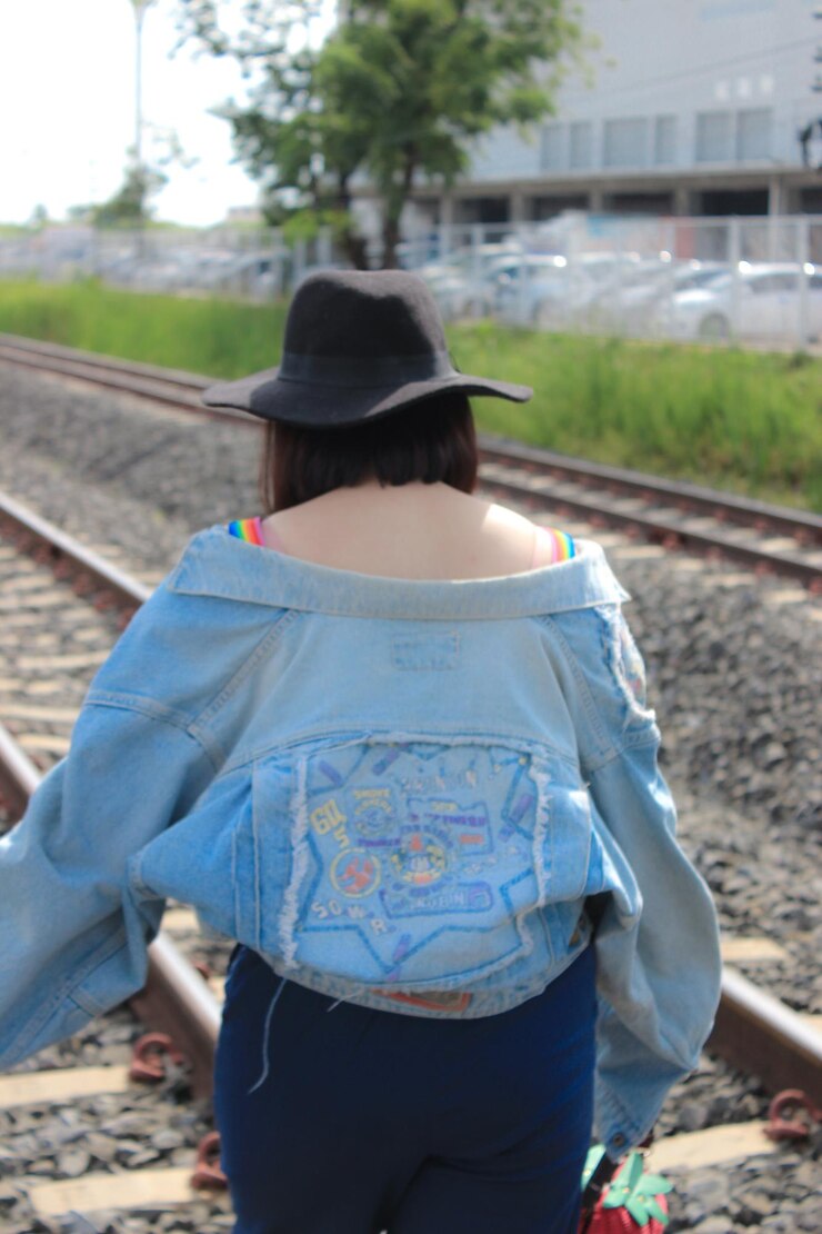 Foto vista traseira de uma jovem vestindo um chapéu caminhando na via ferroviária