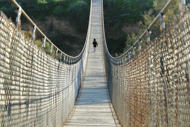 Foto vista traseira de uma menina caminhando na ponte