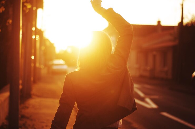 Foto vista traseira de uma menina dançando em meio a edifícios durante o pôr do sol