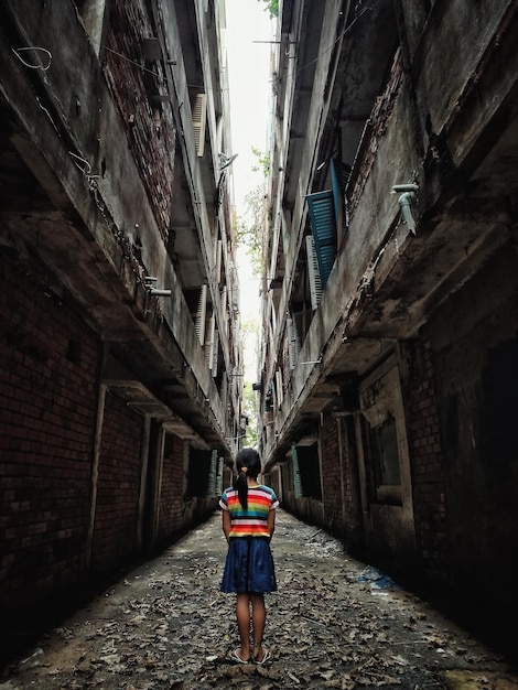 Vista traseira de uma menina de pé no meio de um edifício