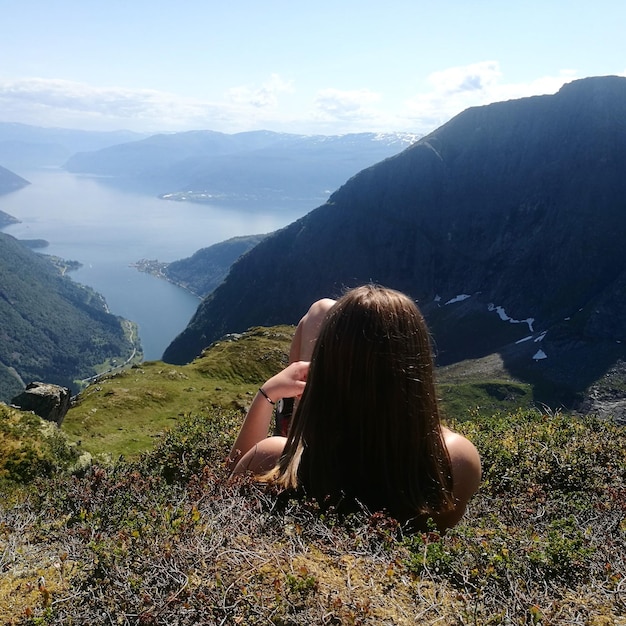 Foto vista traseira de uma menina deitada na montanha contra o fiorde