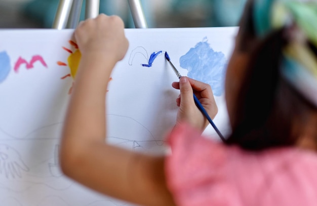 Foto vista traseira de uma menina pintando dentro de casa