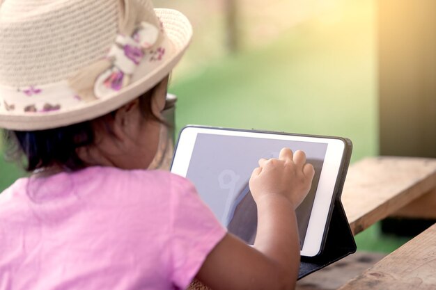 Foto vista traseira de uma menina usando um tablet digital na mesa