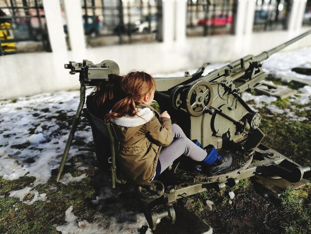 Foto vista traseira de uma menina usando uma arma militar