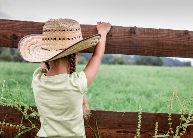 Foto vista traseira de uma menina vestindo um chapéu de pé em terra