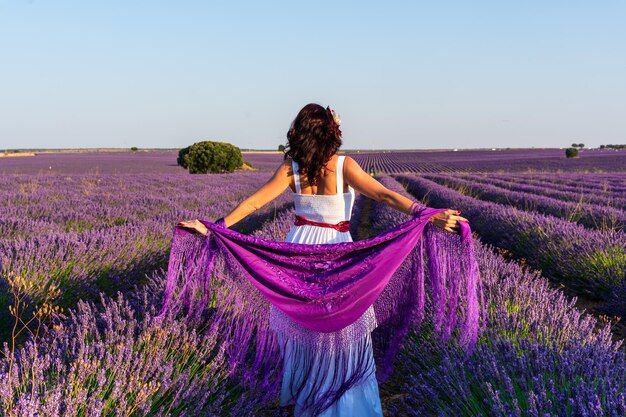 Vista traseira de uma mulher ao ar livre em um campo de flores de lavanda colorido