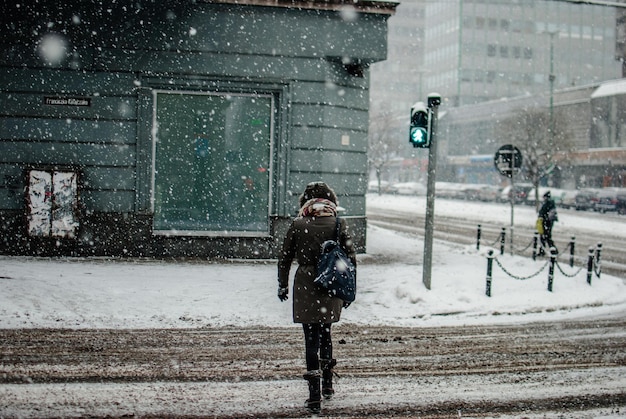 Vista traseira de uma mulher atravessando a rua durante o inverno