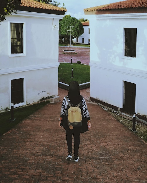 Foto vista traseira de uma mulher caminhando na calçada contra o edifício