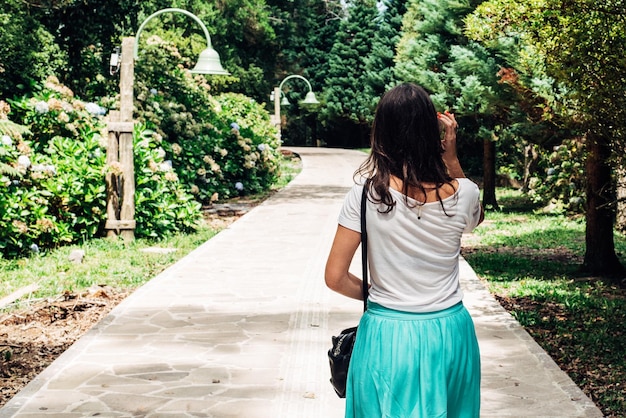 Vista traseira de uma mulher caminhando na calçada no parque