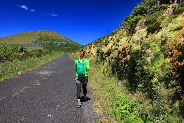Foto vista traseira de uma mulher caminhando na estrada contra a montanha