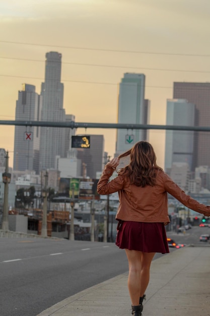 Vista traseira de uma mulher caminhando na estrada contra edifícios