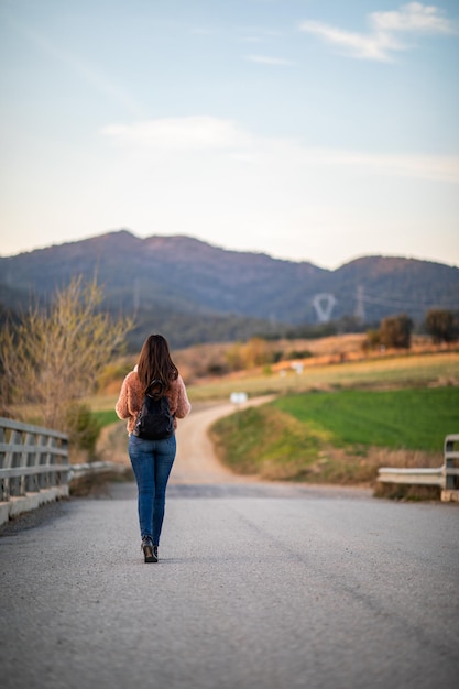 Foto vista traseira de uma mulher caminhando na estrada contra o céu