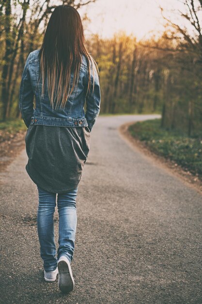 Foto vista traseira de uma mulher caminhando na estrada na floresta