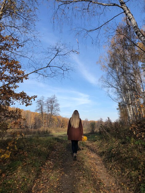 Vista traseira de uma mulher caminhando na floresta