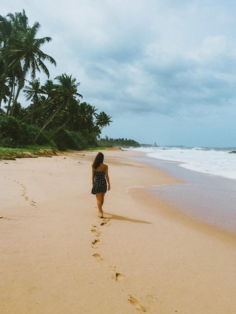 Foto vista traseira de uma mulher caminhando na praia