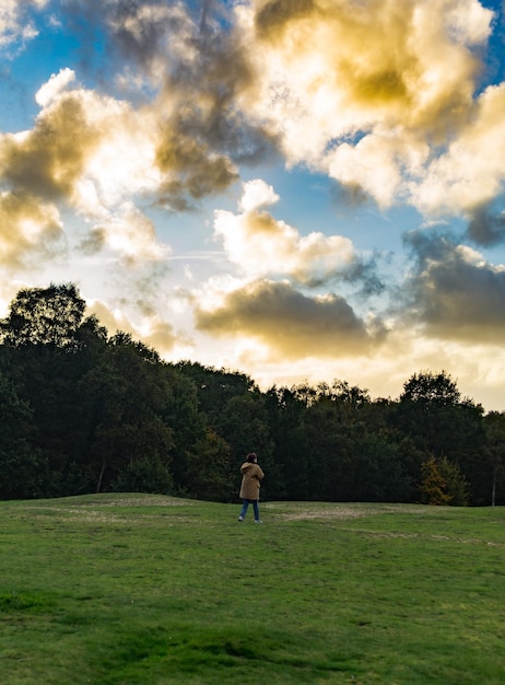 Foto vista traseira de uma mulher caminhando no campo contra o céu durante o pôr do sol