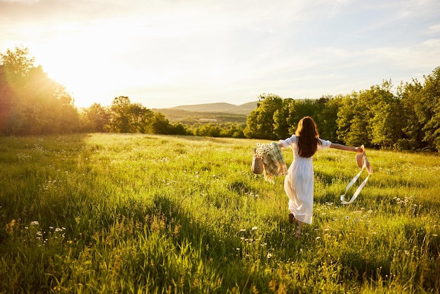 Foto vista traseira de uma mulher caminhando no campo contra o céu