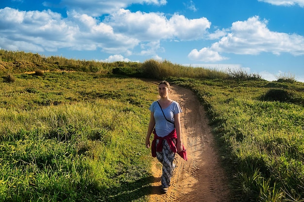 Foto vista traseira de uma mulher caminhando no campo contra o céu
