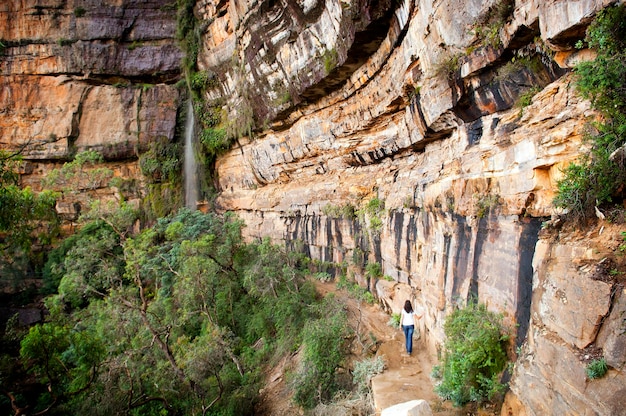 Vista traseira de uma mulher caminhando sobre uma formação rochosa