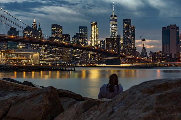 Foto vista traseira de uma mulher com uma ponte iluminada ao fundo