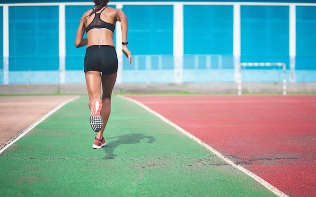 Vista traseira de uma mulher correndo em uma pista de esportes