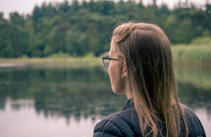 Foto vista traseira de uma mulher de pé ao lado do lago