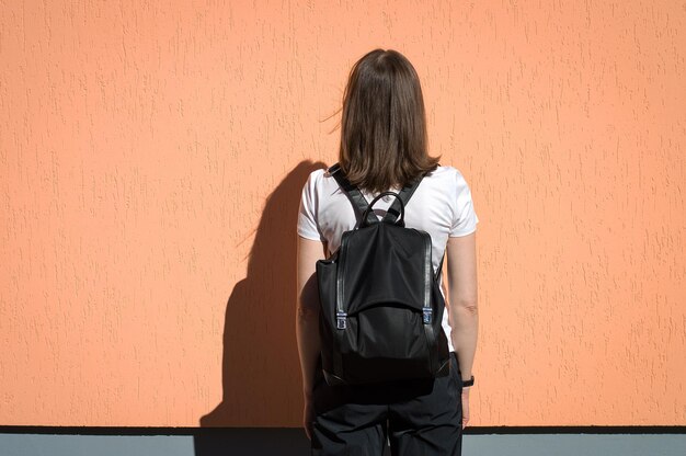 Foto vista traseira de uma mulher de pé contra a parede