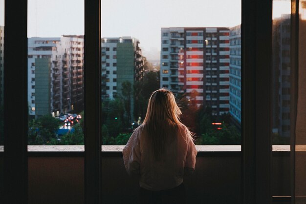 Vista traseira de uma mulher de pé contra edifícios na cidade