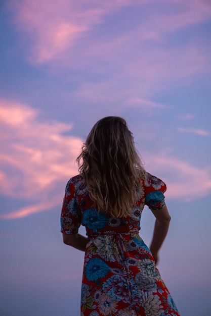 Foto vista traseira de uma mulher de pé contra o céu durante o pôr do sol