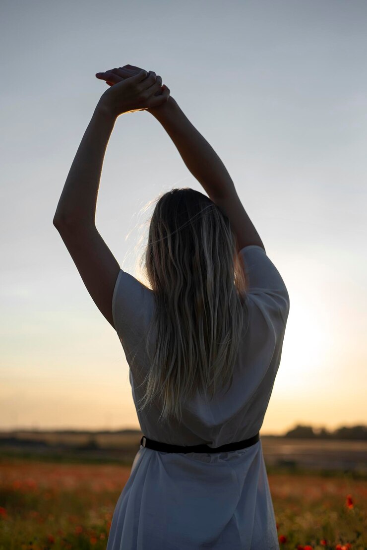Foto vista traseira de uma mulher de pé contra o céu durante o pôr do sol