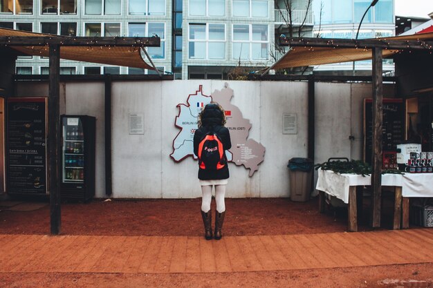 Foto vista traseira de uma mulher de pé contra o mapa na parede