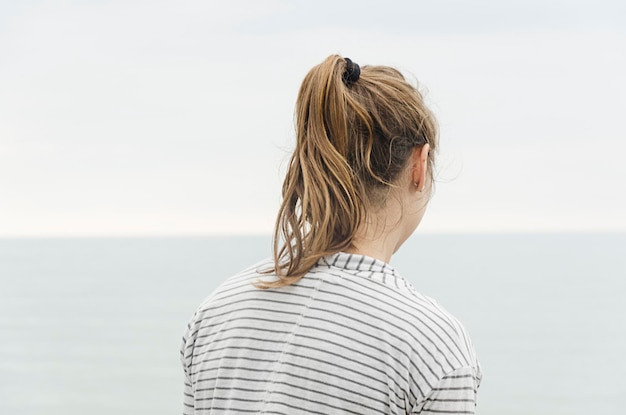 Vista traseira de uma mulher de pé contra o mar