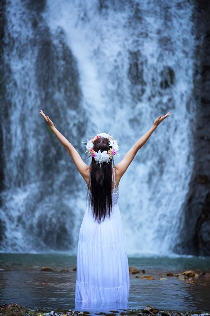 Foto vista traseira de uma mulher de pé contra uma cachoeira