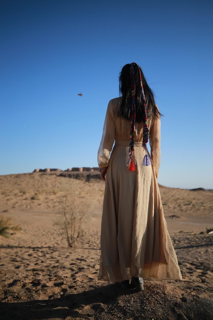 Foto vista traseira de uma mulher de pé em terra contra um céu azul claro
