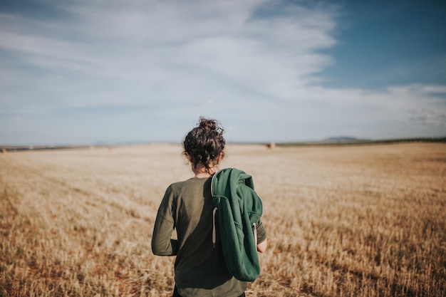 Vista traseira de uma mulher de pé em um campo de trigo contra o céu