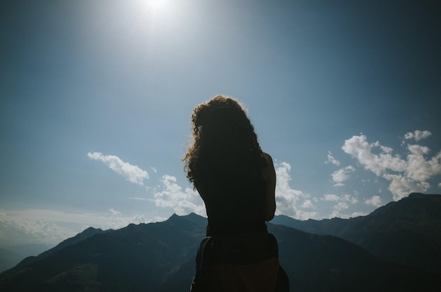 Vista traseira de uma mulher de pé na montanha contra o céu