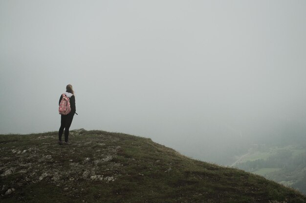 Foto vista traseira de uma mulher de pé na montanha contra o céu