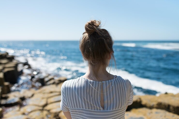 Foto vista traseira de uma mulher de pé na praia contra o céu claro