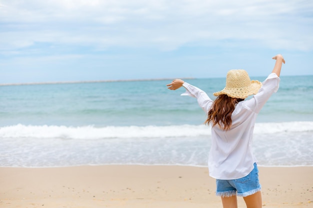 Vista traseira de uma mulher de pé na praia contra o céu