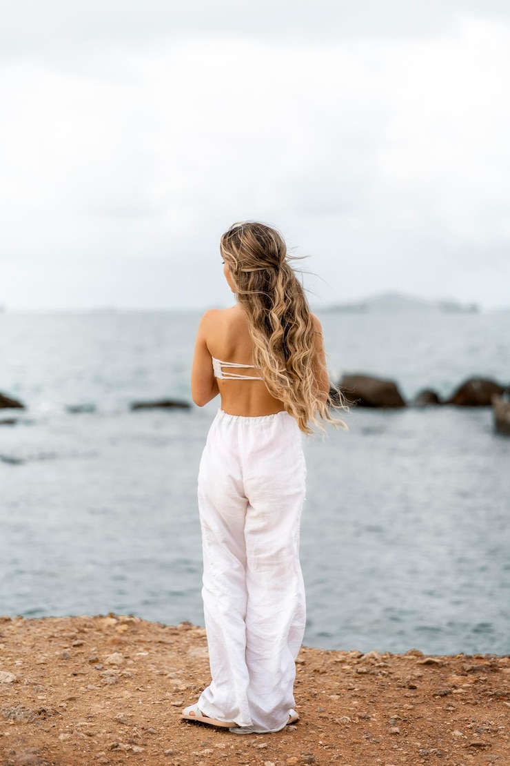 Foto vista traseira de uma mulher de pé na praia contra o céu