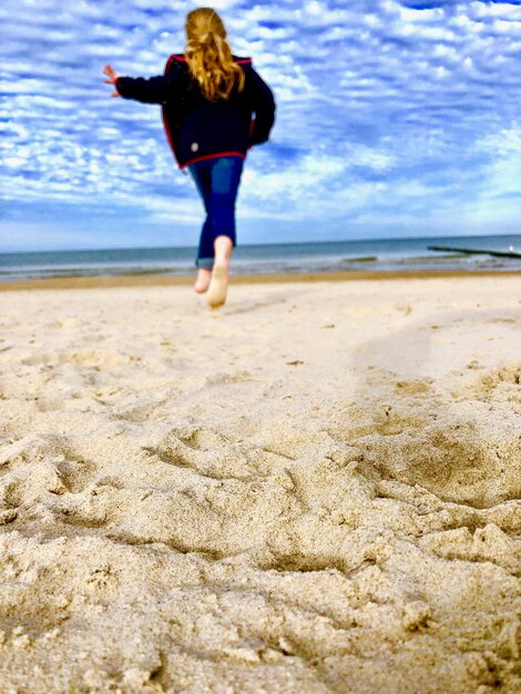 Foto vista traseira de uma mulher de pé na praia