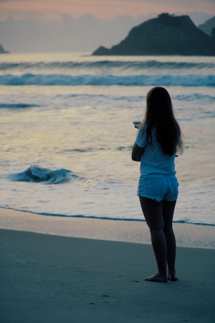 Foto vista traseira de uma mulher de pé na praia